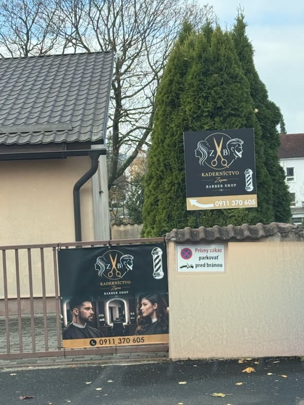 Vstup do salónu z ulice: tabuľa Kaderníctvo Zuzana & Barber Shop s telefónom a plagát na bráne